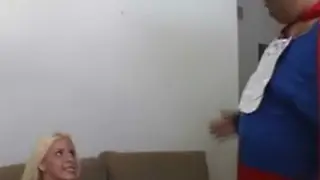 Мужчина одетый как Супермен соблазняет женщину на диване